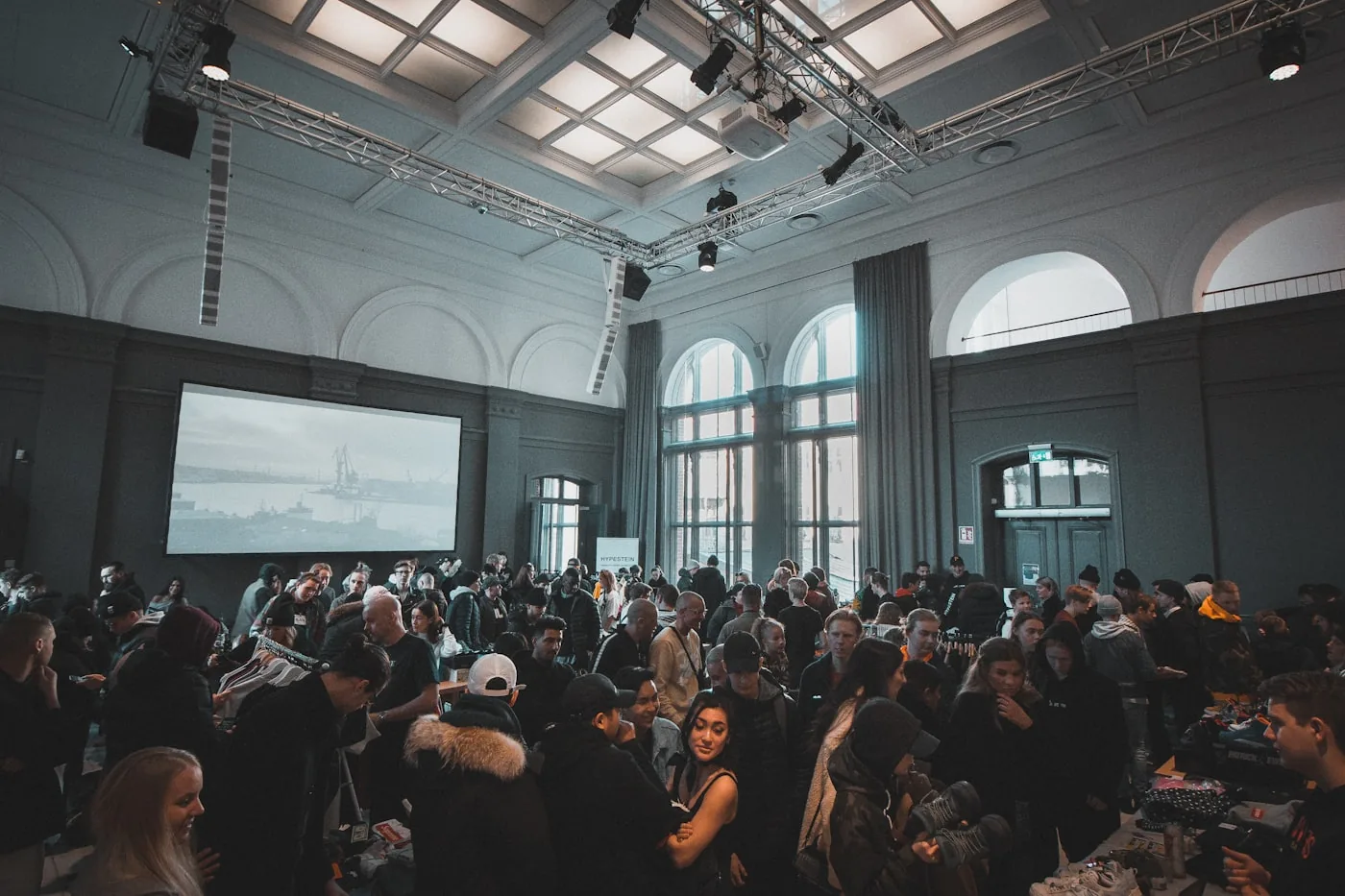 An audience seated in a hall in front of a large projection screen