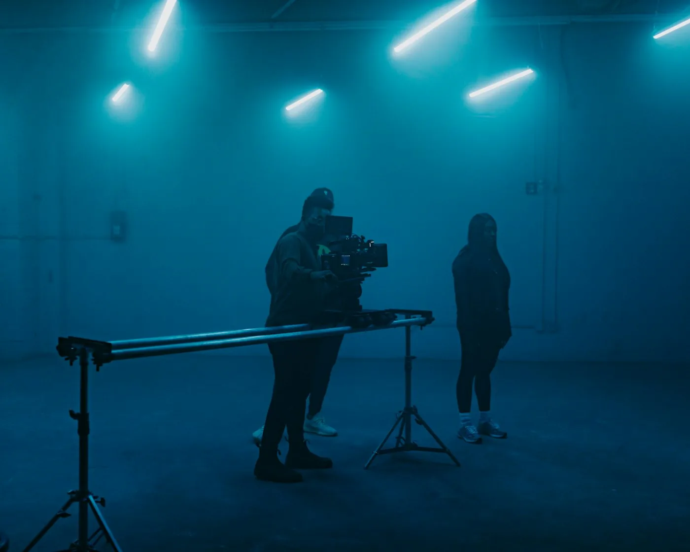 Two crew members filming inside a blue-lit sound stage