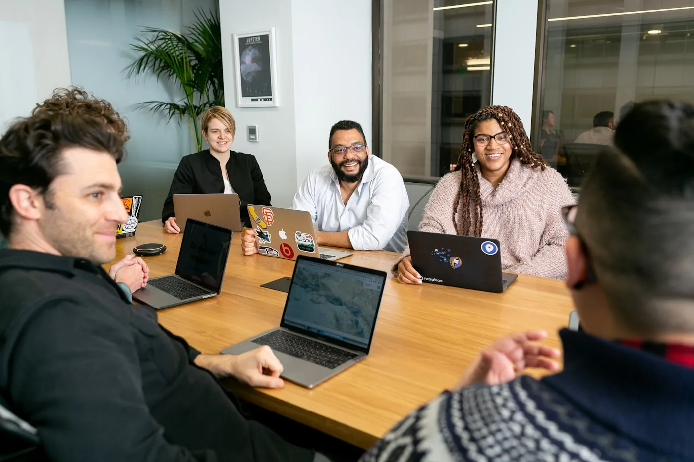 A working meeting around a boardroom table with laptops and notes