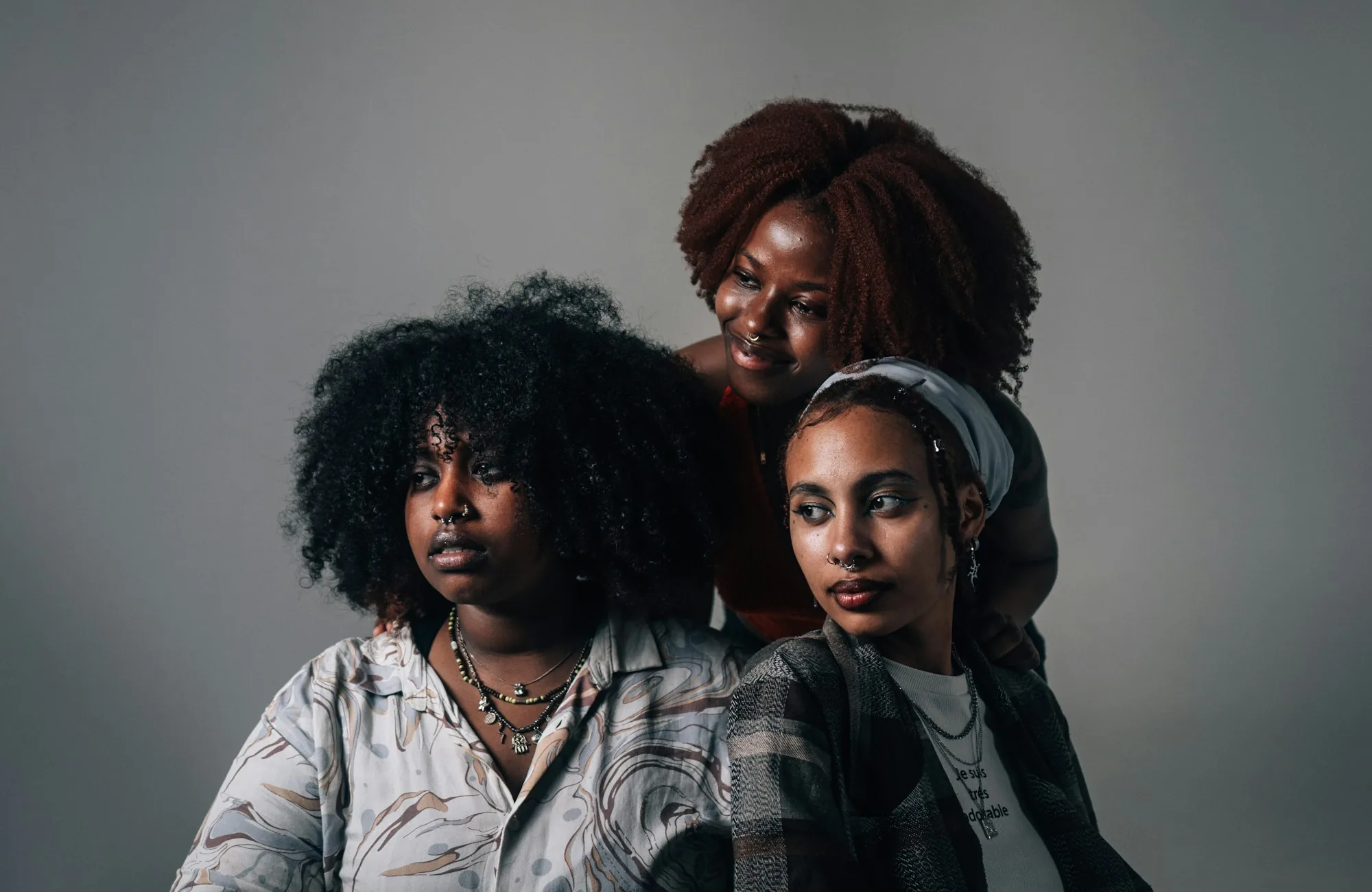 Three young women in a composed studio portrait, confident and self-possessed