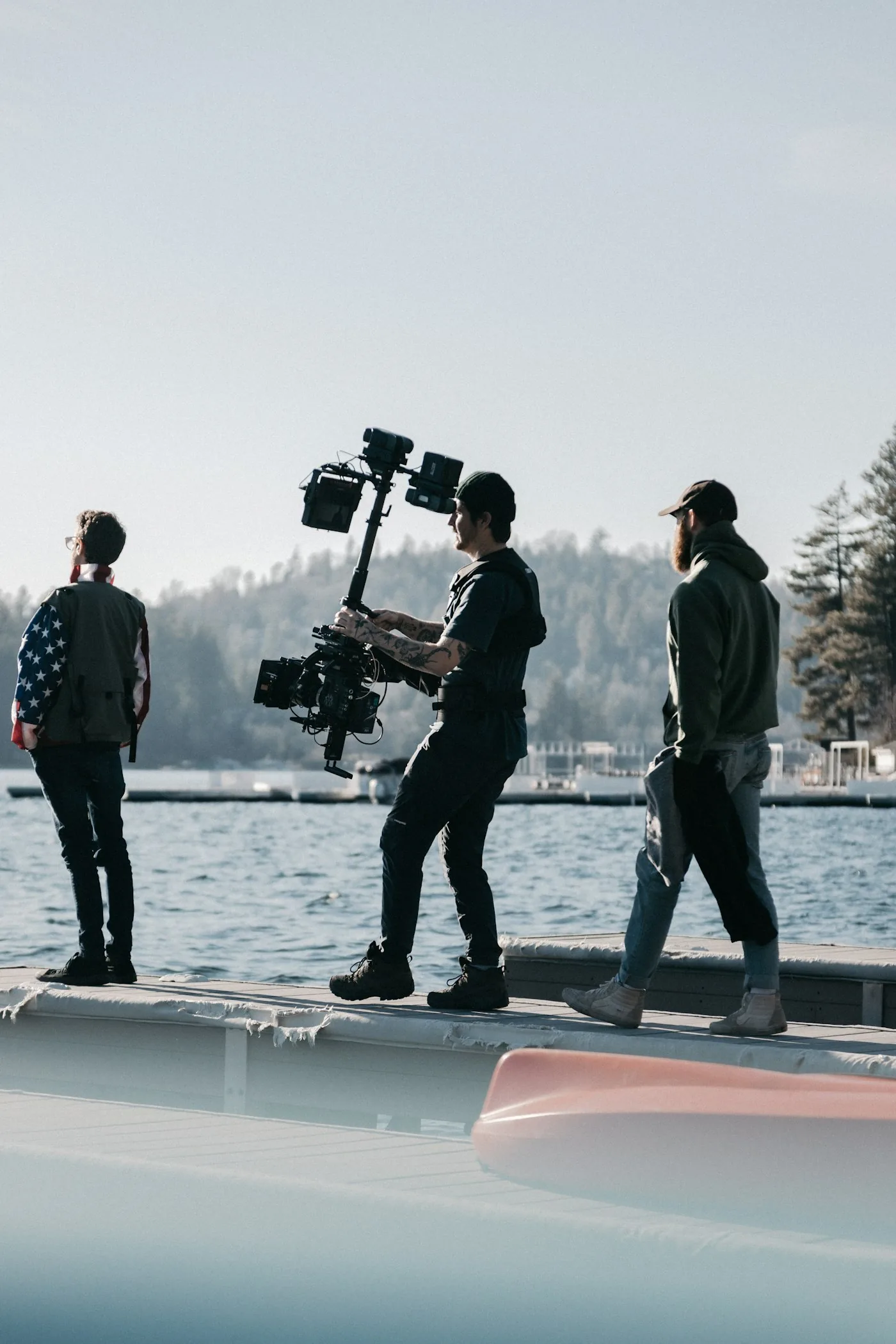A small documentary crew carrying a gimbal-mounted camera on location by the water