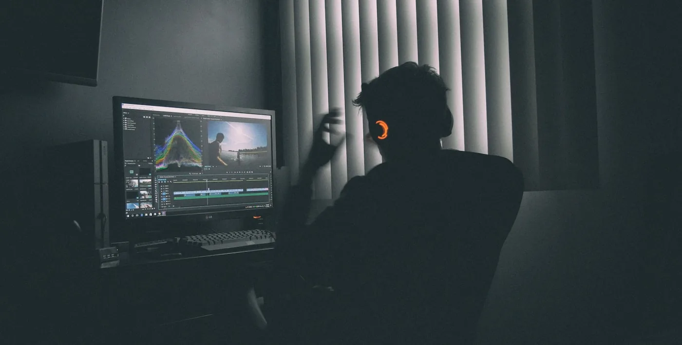 An editor working at a colour-lit screen late in the evening