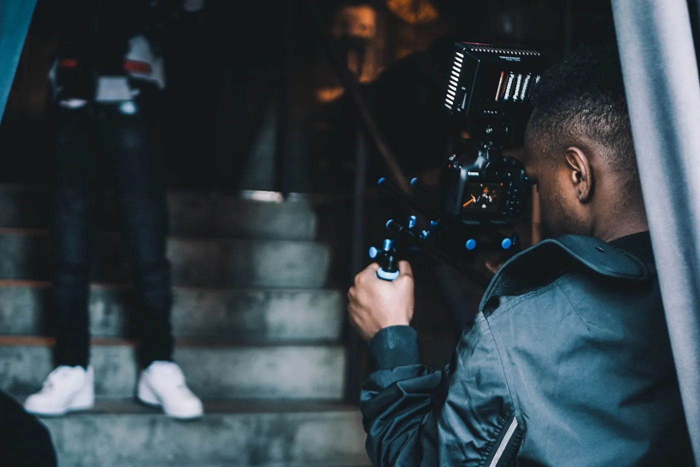 A camera operator filming a person on location in an urban setting