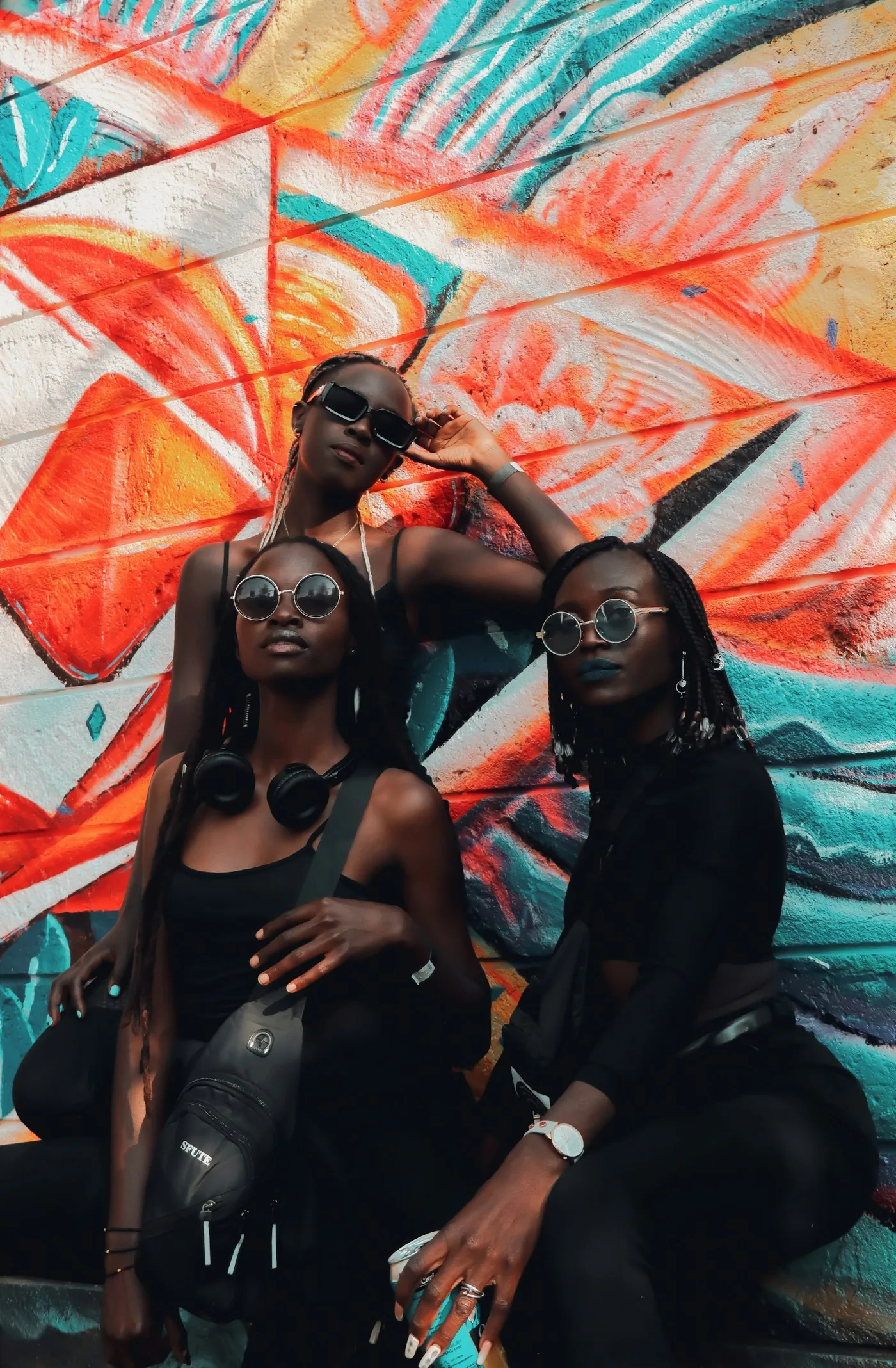 Two young women photographed against a bright graffiti mural